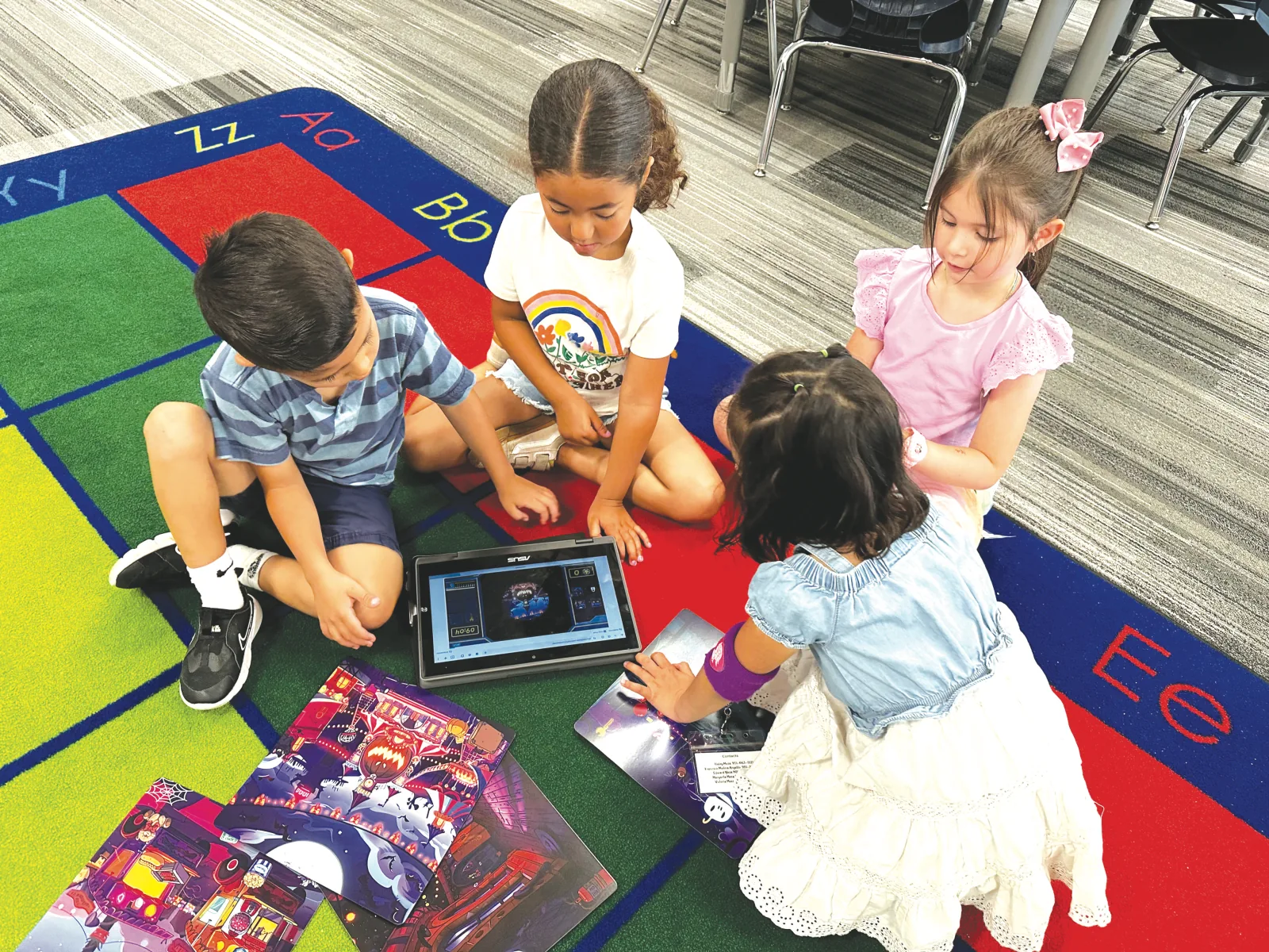 Kids gathered on a rug around a tablet and mission cards